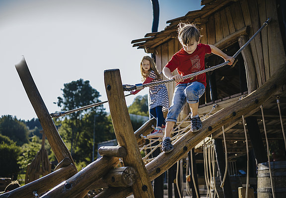 Das Bild zeigt zwei Kinder, die auf einem Klettergerüst eines Spielplatzes beim Freizeitzentrum Peterberg klettern.