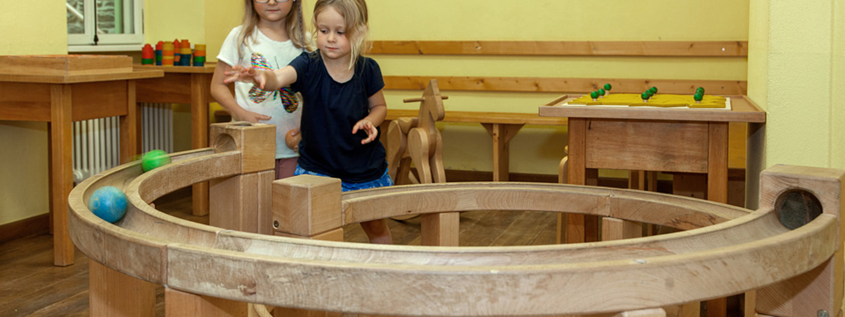 Das Bild zeigt zwei Mädchen, die mit einer Kugelbahn im Spielzimmer des Hunsrücker Holzmuseums spielen.