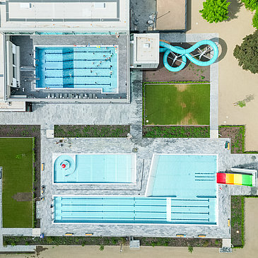 Das Foto zeigt die Gesamtanlage des Vitteliusbad Wittlich, mit Hallenbad, Freibad, Rutschen, Liegewiesen und Kinderbereich.