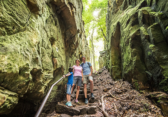 Das Bild zeigt eine Familie auf dem Wanderweg Teufelsschlucht zwischen Felsen.