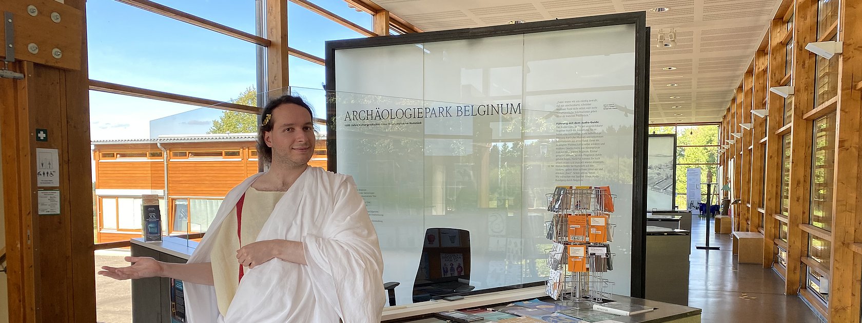 Das Bild zeigt eine römische Figur und die Dauerausstellung im Kulturzentrum Belginum Archäologiepark.